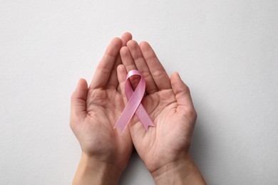 Photo of Woman holding pink ribbon on white background, top view. Breast cancer awareness concept