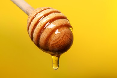 Pouring honey from dipper against golden background, closeup. Space for text
