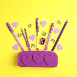 Image of Purple pencil case and stationery on yellow background, flat lay