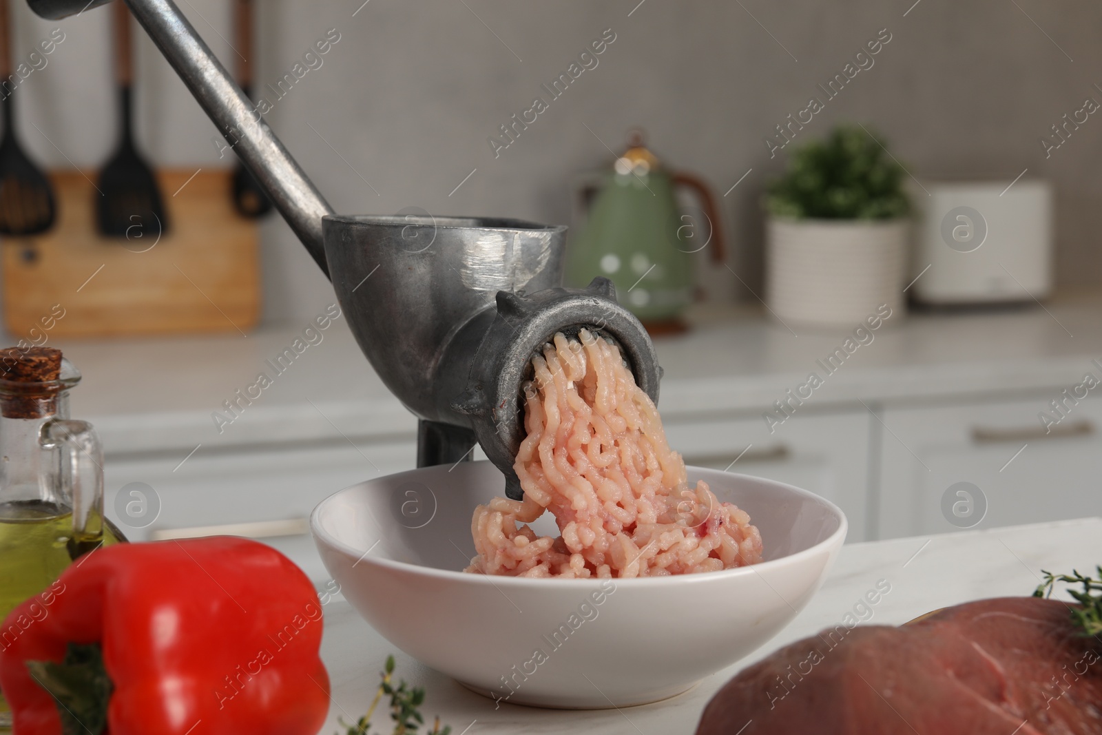 Photo of Metal meat grinder with chicken mince and products on white table in kitchen