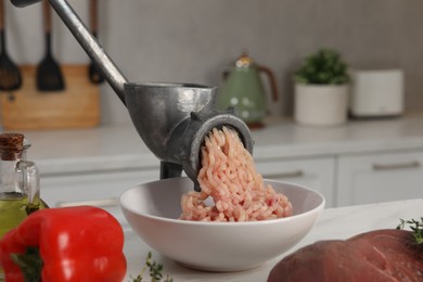 Photo of Metal meat grinder with chicken mince and products on white table in kitchen