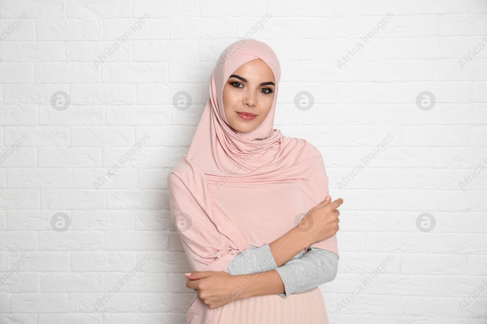 Photo of Portrait of young Muslim woman in hijab against brick wall