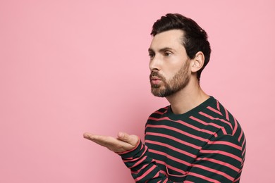 Handsome man blowing kiss on pink background. Space for text