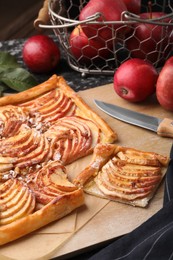 Photo of Tasty apple pie, knife and fresh fruits on table