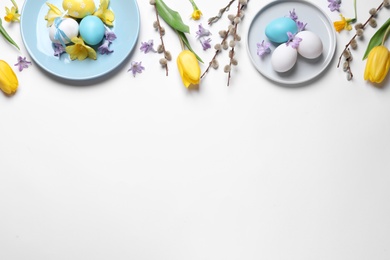 Photo of Festive Easter table setting with painted eggs and floral decor on white background, flat lay. Space for text