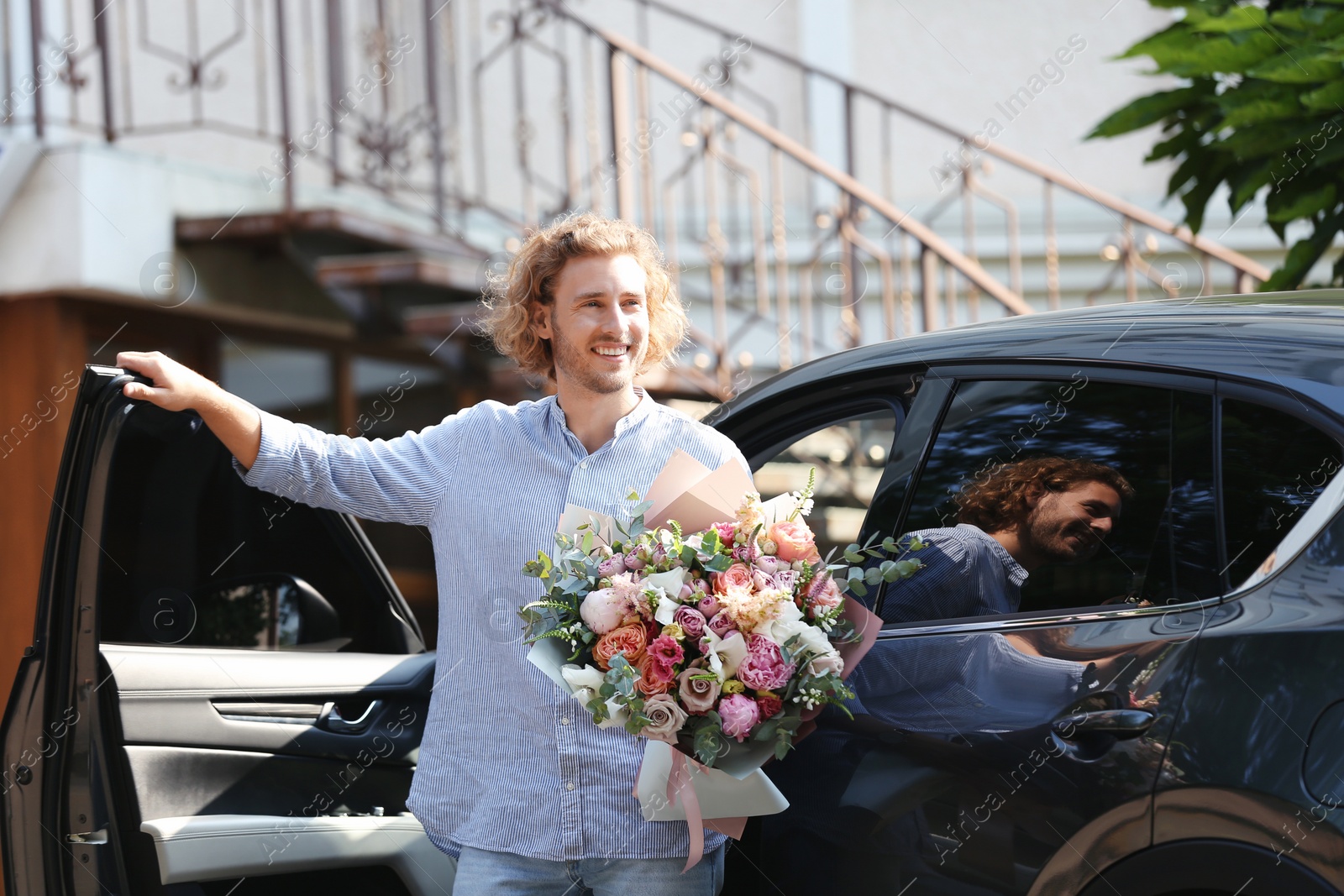 Photo of Young handsome man with beautiful flower bouquet near car on street