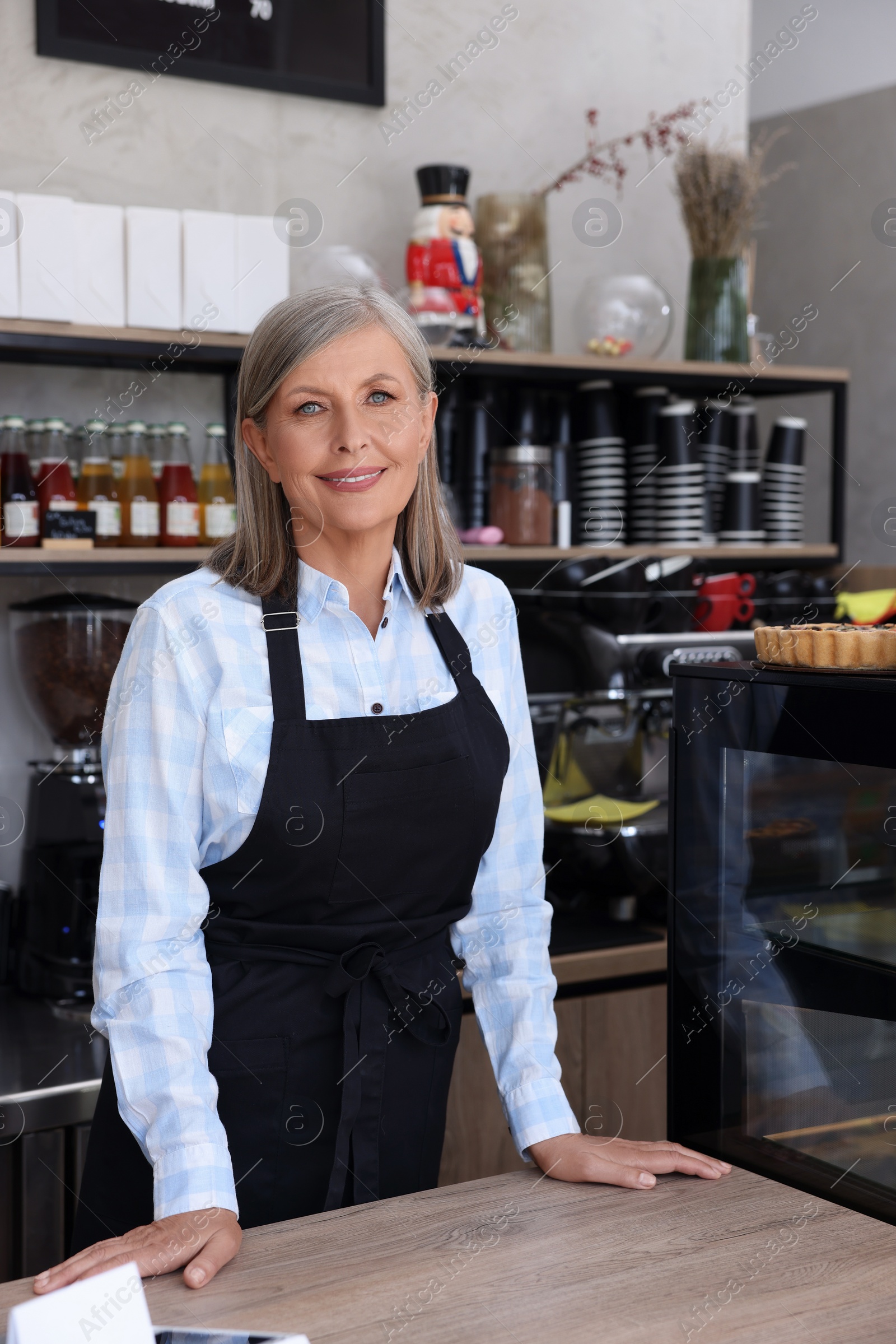 Photo of Portrait of happy business owner at cashier desk in her coffee shop