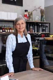 Photo of Portrait of happy business owner at cashier desk in her coffee shop