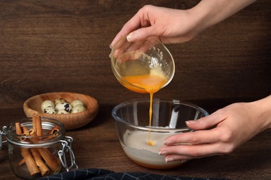 Photo of Woman mixing ingredients at wooden table, closeup. Cooking delicious eggnog