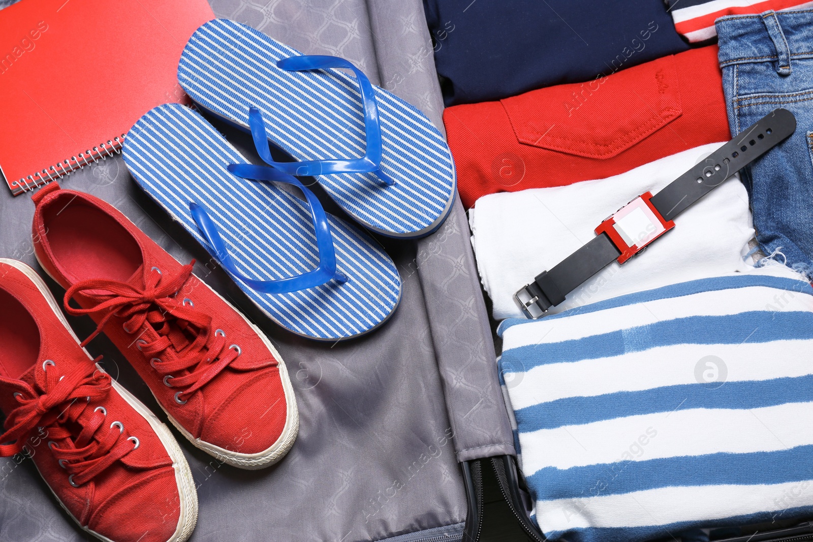 Photo of Packed suitcase with clothes and shoes, closeup view