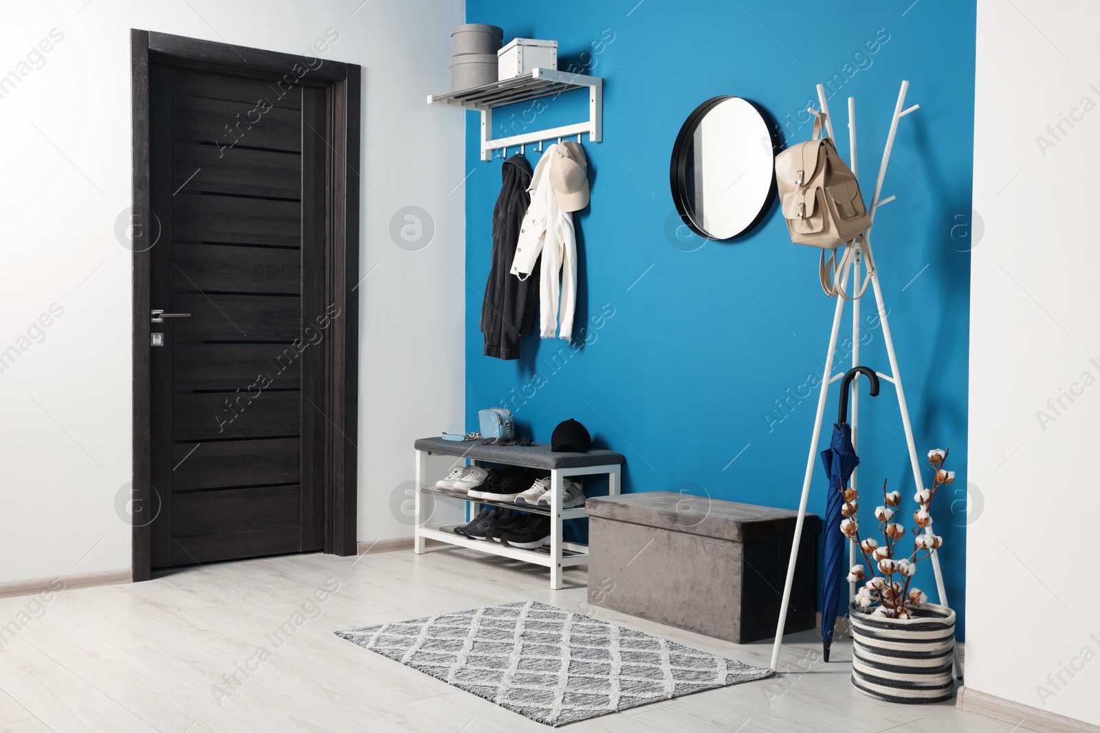 Photo of Stylish hallway with coat rack and shoe storage bench near blue wall. Interior design