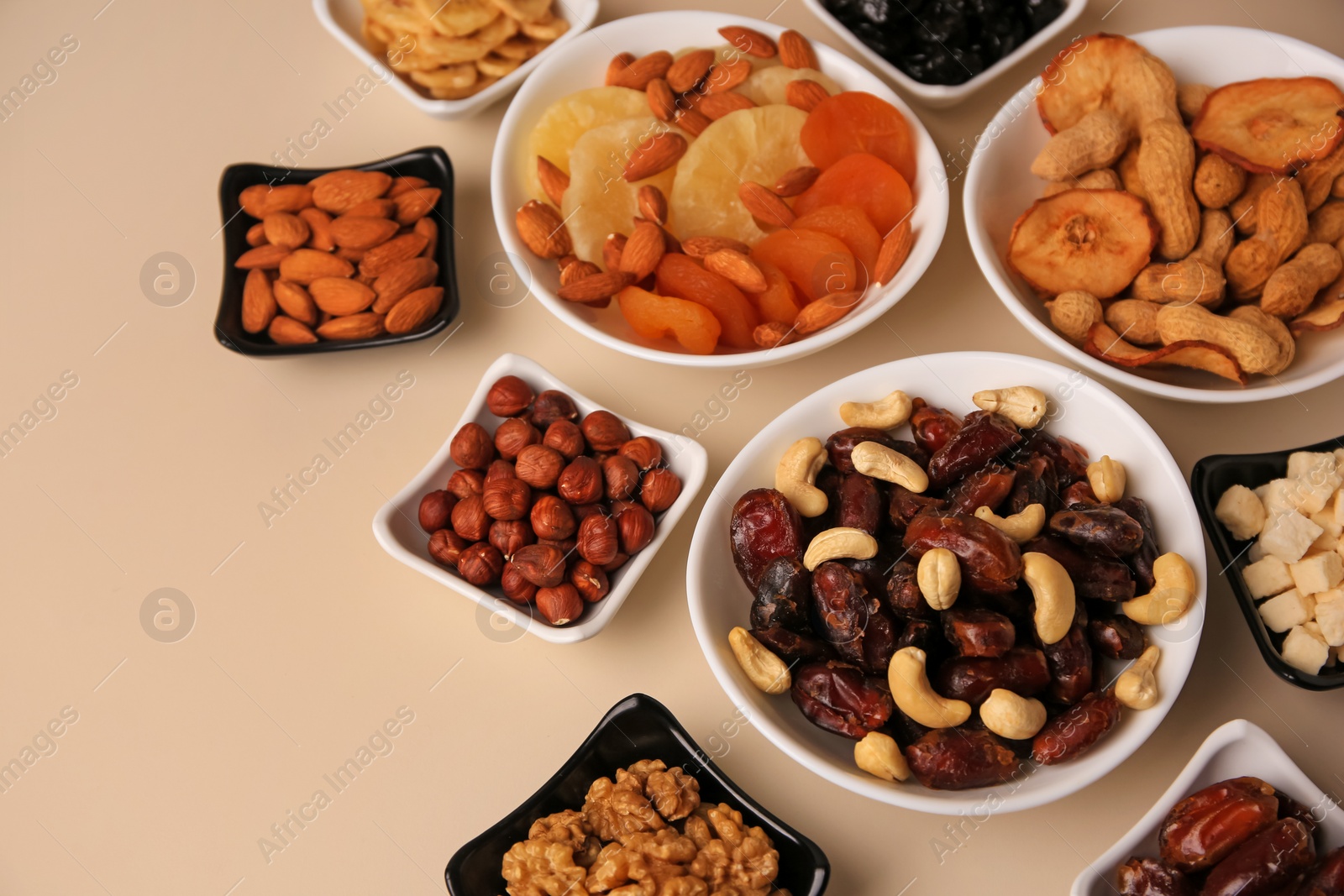 Photo of Bowls with dried fruits and nuts on beige background, above view. Space for text