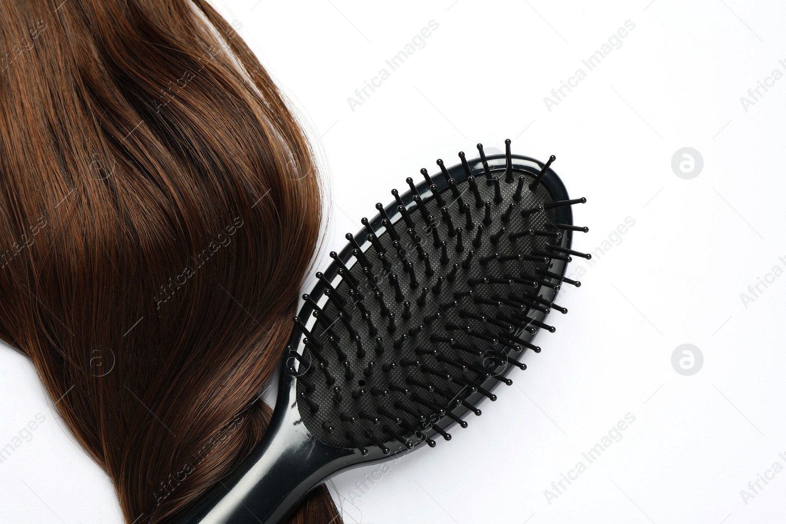 Photo of Stylish brush with brown hair strand on white background, top view