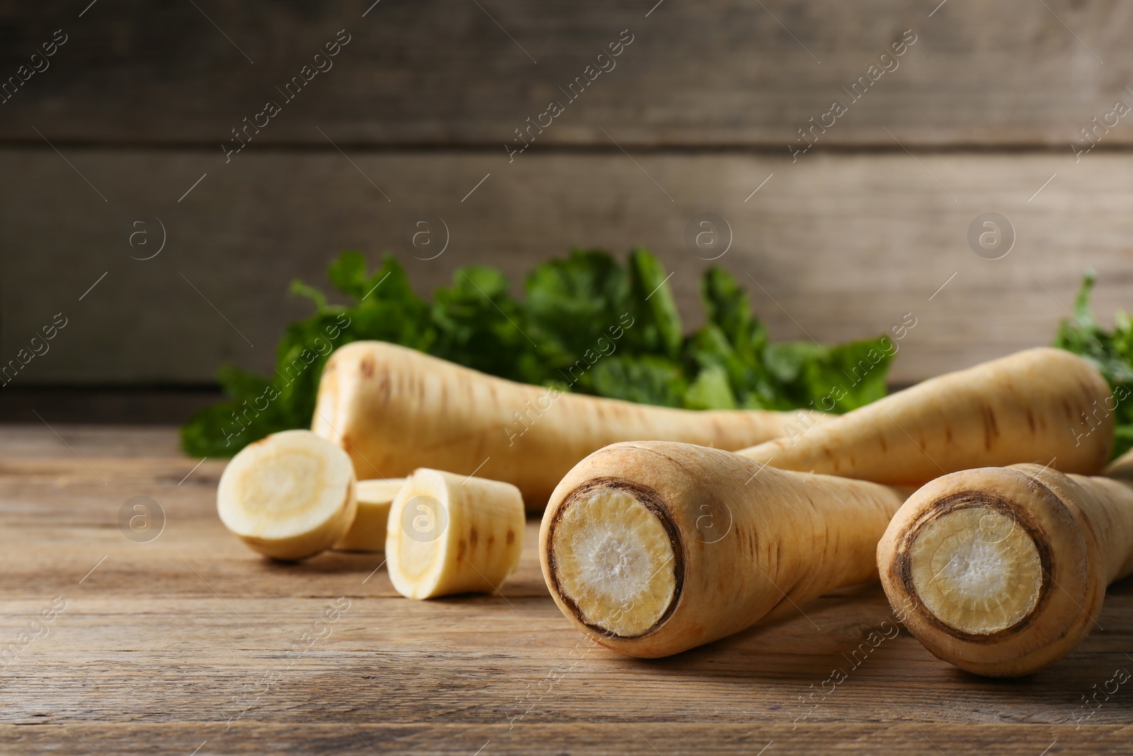 Photo of Fresh ripe parsnips on wooden table, closeup. Space for text