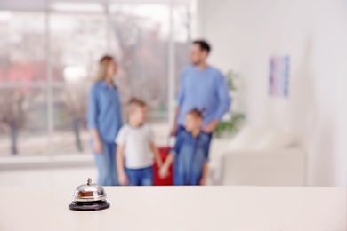 Photo of Hotel service bell on reception desk and blurred family on background