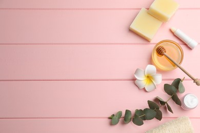 Flat lay composition with beeswax and cosmetic products on pink wooden table. Space for text