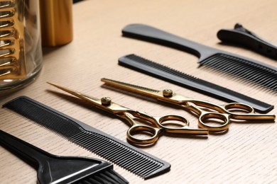 Photo of Hairdresser tools. Different scissors and combs on wooden table in salon, closeup