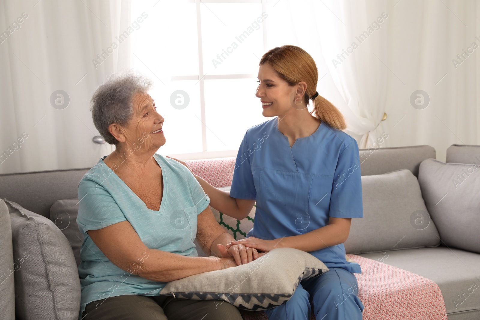 Photo of Nurse holding elderly woman's hands indoors. Assisting senior people