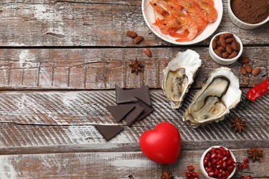 Photo of Natural aphrodisiac. Different food products and heart model on wooden table, flat lay. Space for text