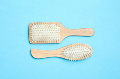 Modern hair brushes on light blue background, flat lay