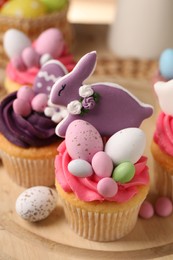 Photo of Tasty cupcakes with Easter decor on wooden board, closeup