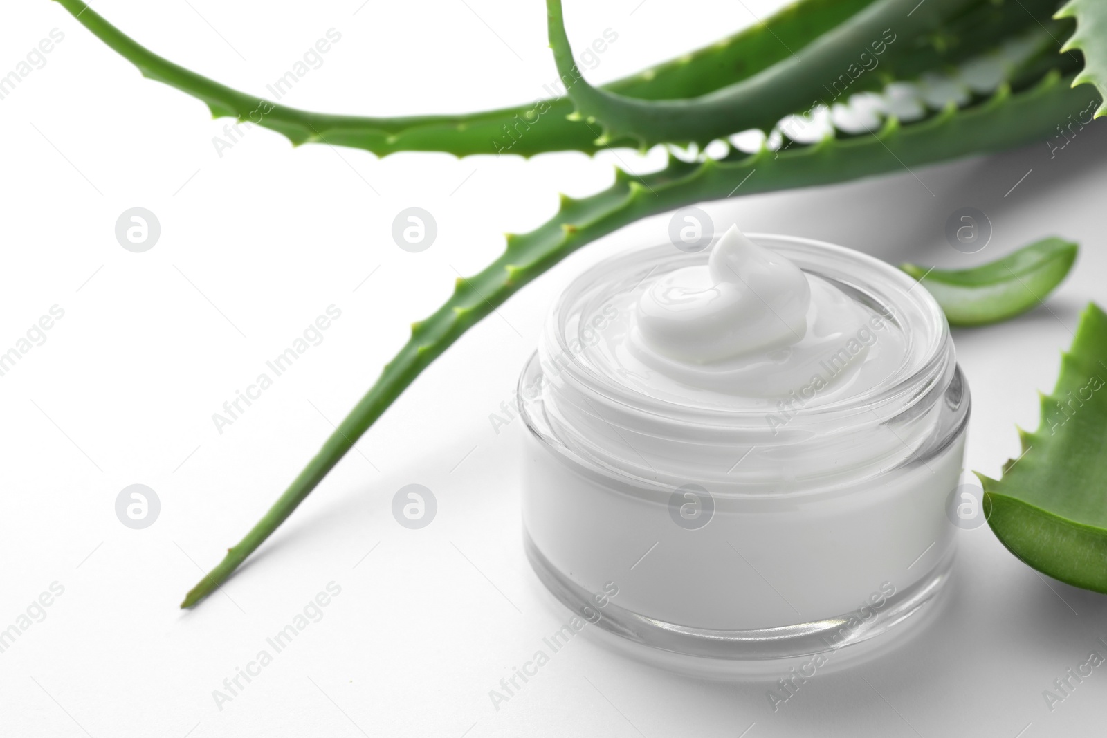 Photo of Jar of natural cream and aloe leaves on white background, closeup. Space for text