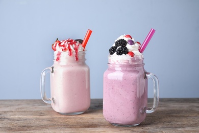 Photo of Tasty milk shakes in mason jars on wooden table