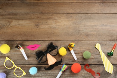 Flat lay composition with clown's items on wooden table, space for text