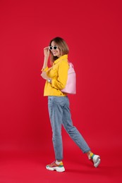 Happy woman with backpack on red background