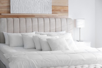 Photo of Comfortable bed with soft white pillows indoors