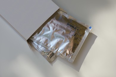 Photo of Package with single dose eye drops on white table, above view