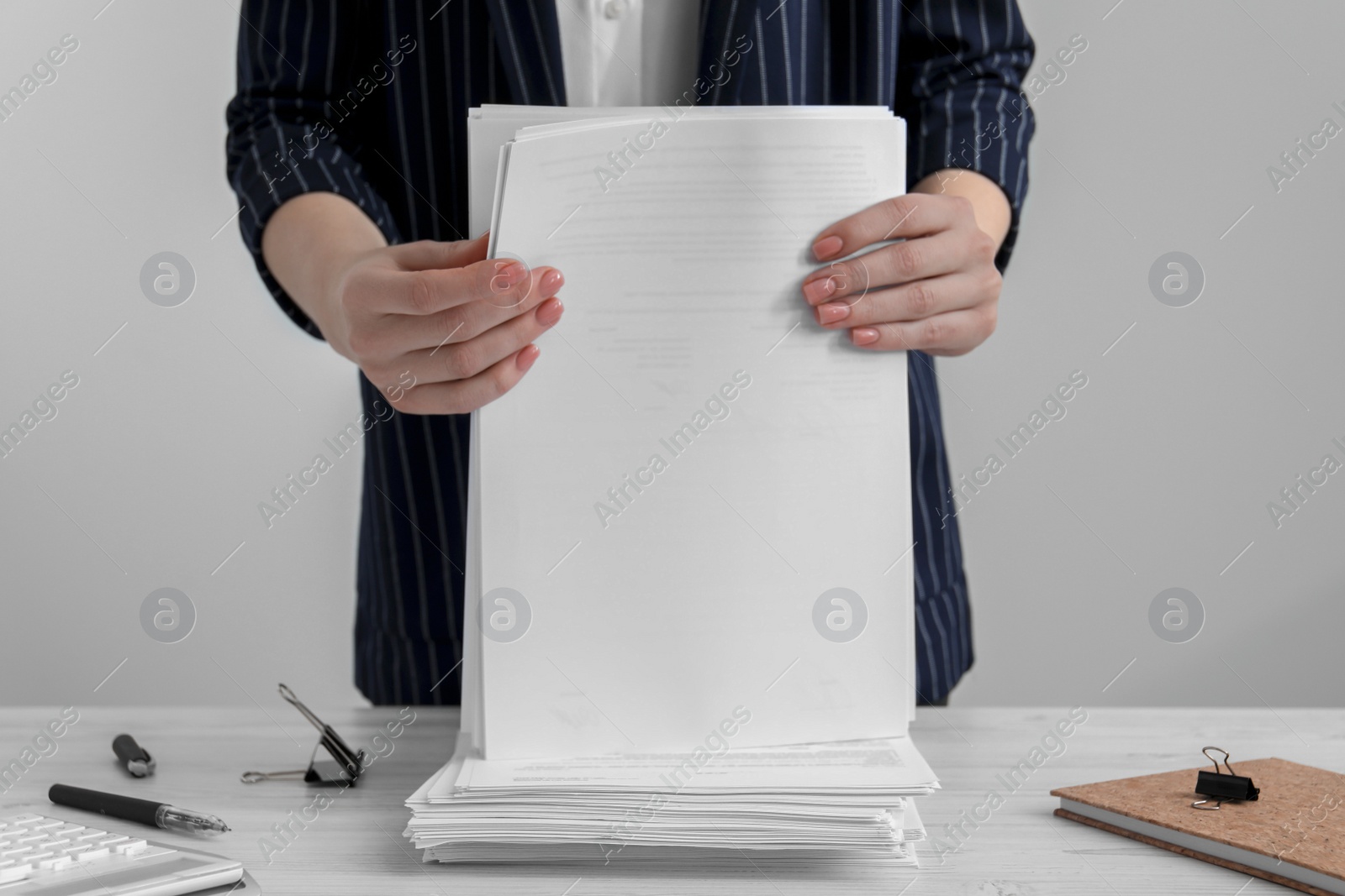 Photo of Woman stacking documents at white wooden table in office, closeup