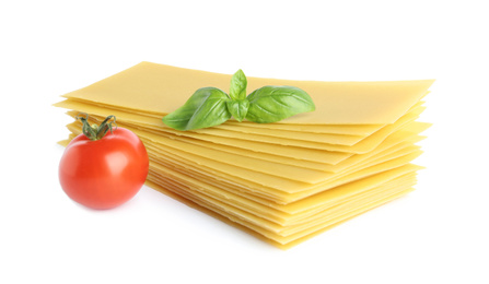 Photo of Uncooked lasagna sheets, tomato and basil on white background