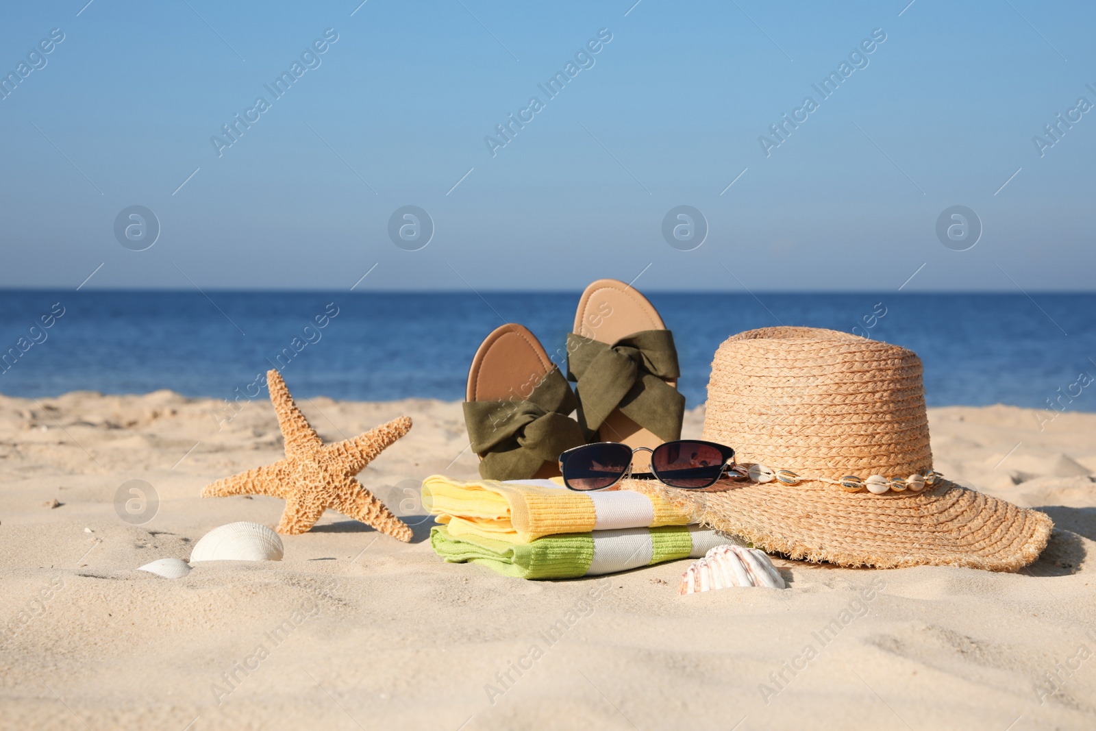 Photo of Stylish beach accessories on sand near sea