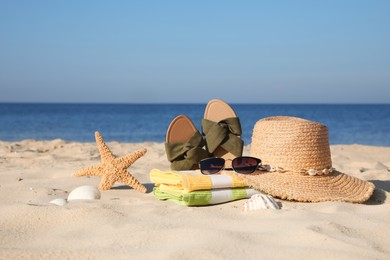 Stylish beach accessories on sand near sea