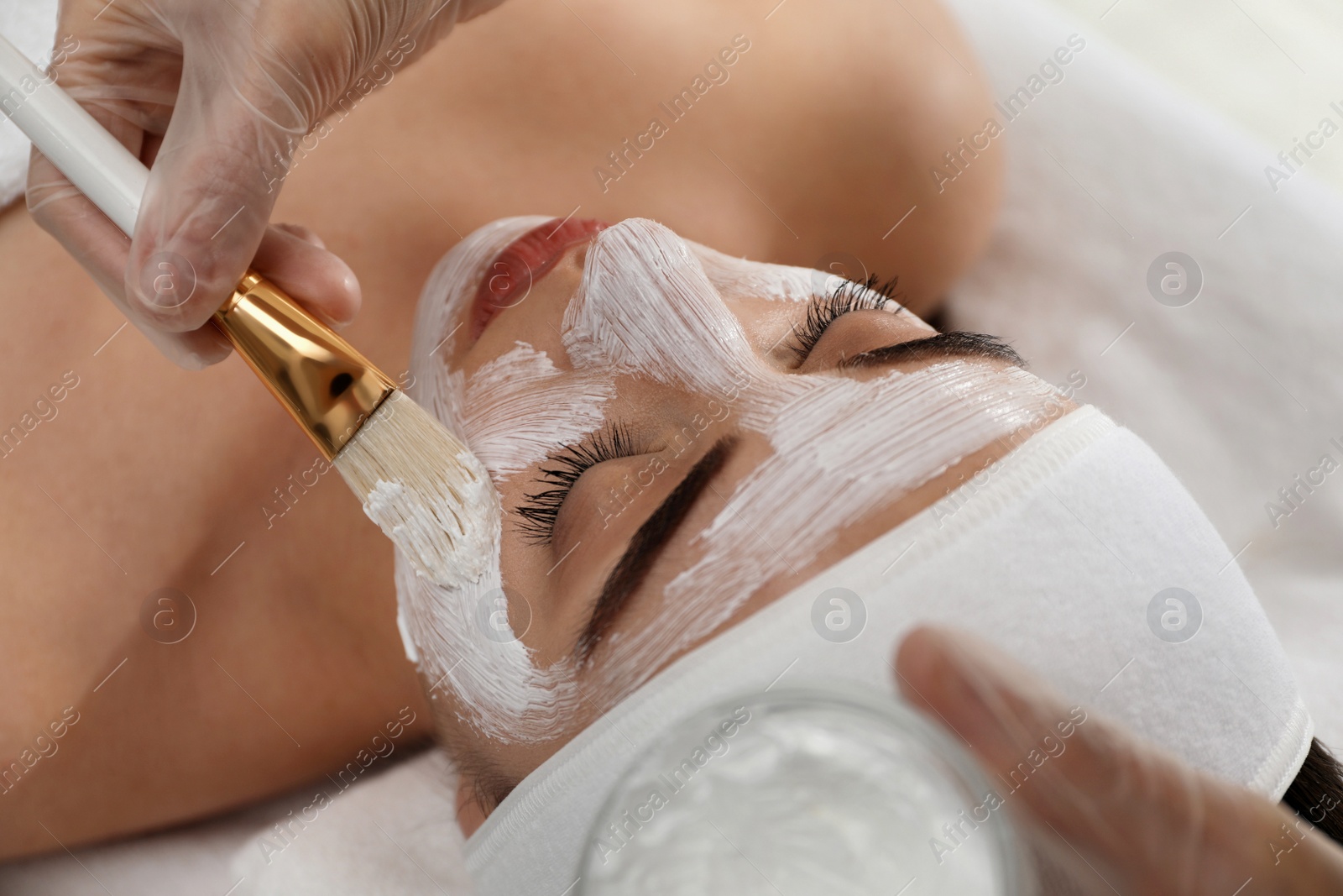 Photo of Young woman during face peeling procedure in salon, closeup