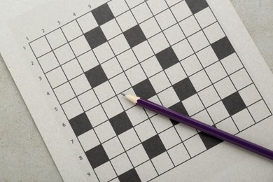 Photo of Blank crossword and pencil on old white table, top view