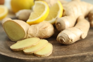 Photo of Fresh lemon and ginger on wooden board, closeup