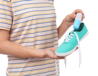 Photo of Woman putting capsule shoe freshener in footwear on white background