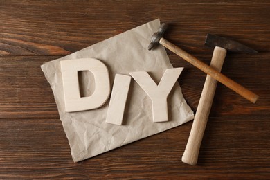 Photo of Abbreviation DIY made of letters and hammers on wooden table, flat lay