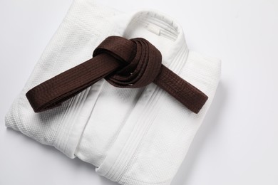 Photo of Brown karate belt and kimono on white background, top view