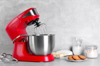 Photo of Modern red stand mixer, cookies and ingredients on light gray marble table. Space for text