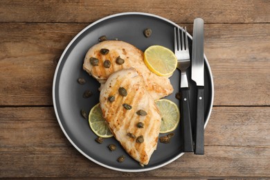 Photo of Delicious chicken fillets with capers and lemon served on wooden table, top view