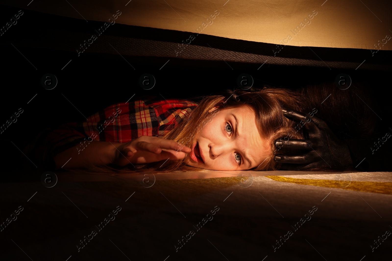 Photo of Childhood phobia. Little girl with monster under bed at home, closeup