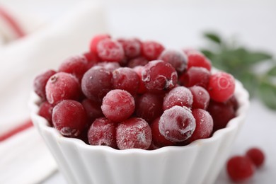 Photo of Frozen red cranberries in bowl on table, closeup