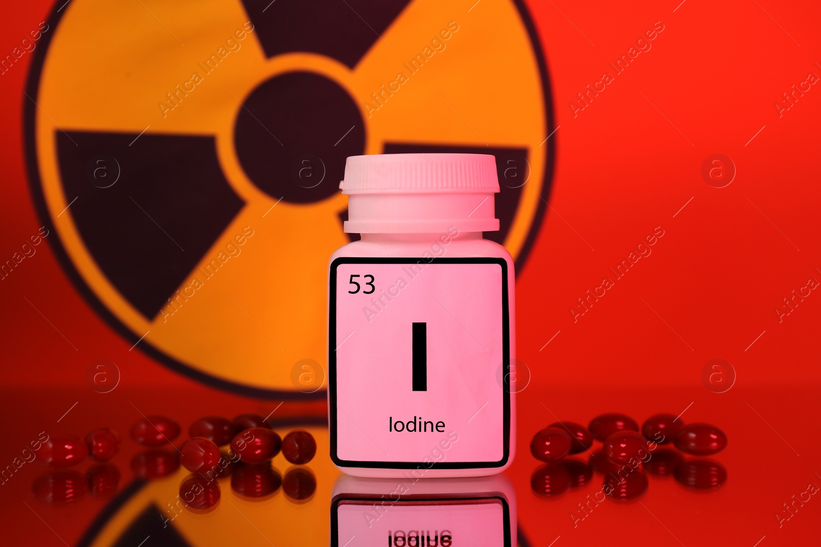Photo of Bottle of medical iodine, pills and radiation sign on red background, color tone effect