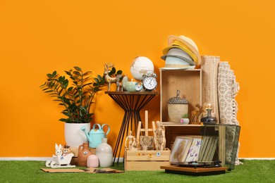 Photo of Many different items near orange wall in room. Garage sale