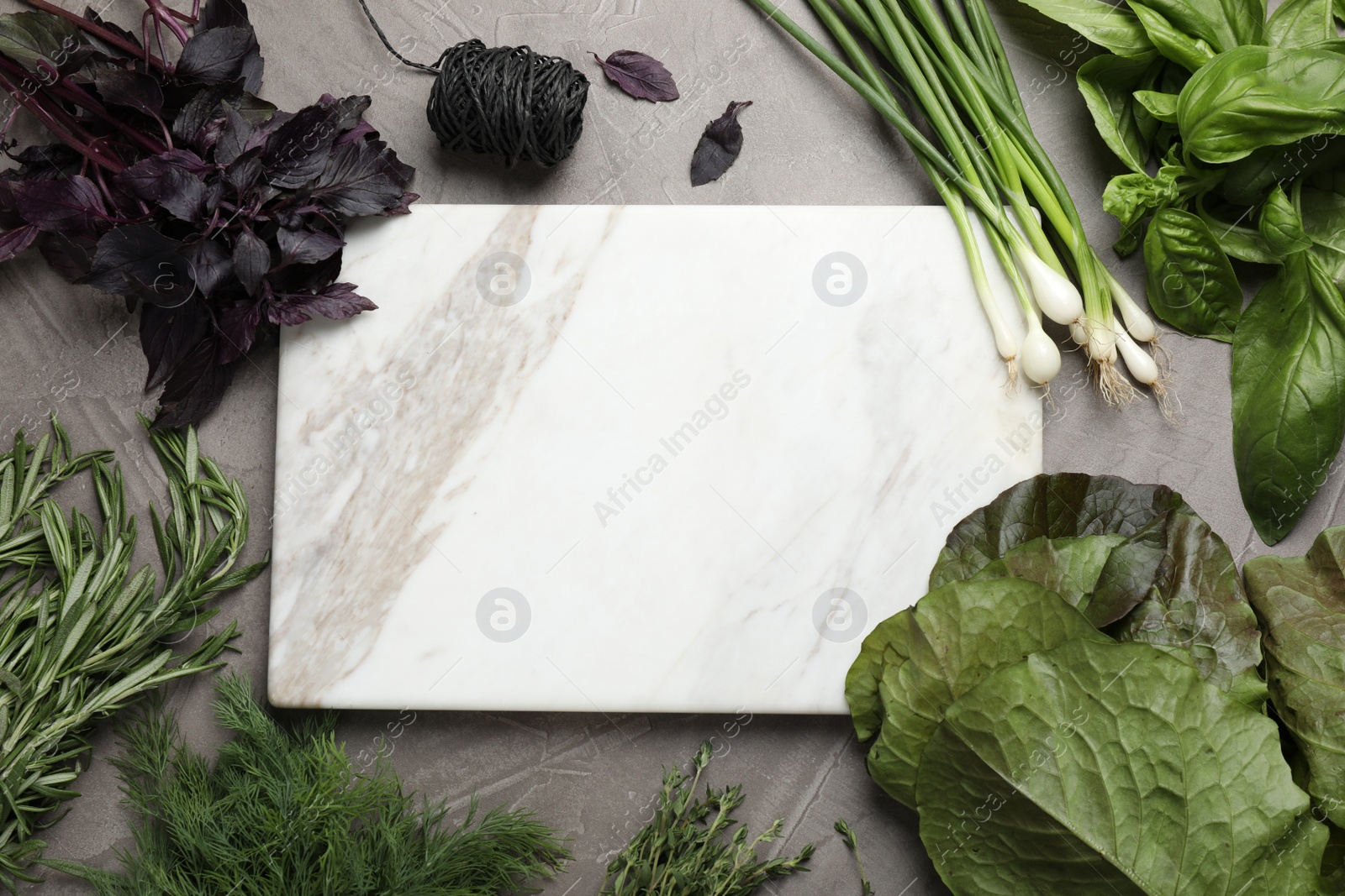 Photo of Different herbs and marble cutting board on grey table, flat lay. Space for text