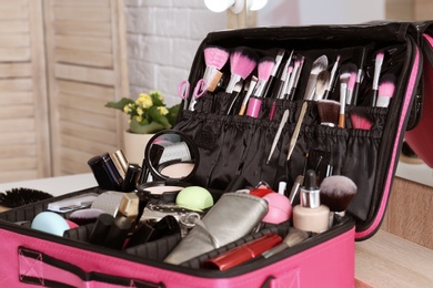 Beautician case with professional makeup products and tools on dressing table