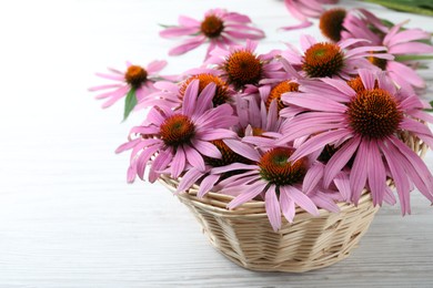 Beautiful echinacea flowers in wicker basket on white wooden table